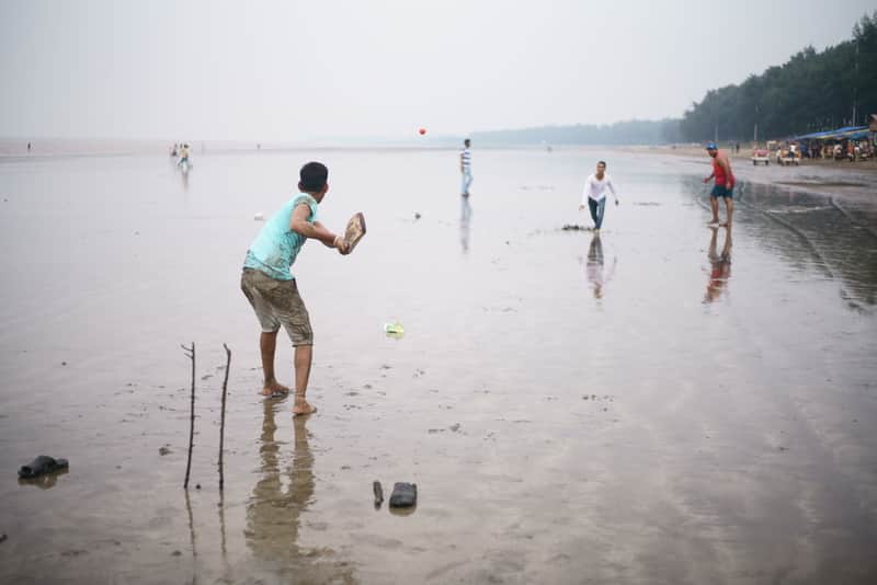 Kids playing cricket on a beach in Daman