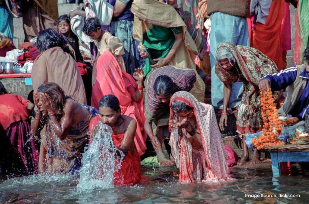 Women take holy dip and perform araghya to Sun on Chhath Puja.